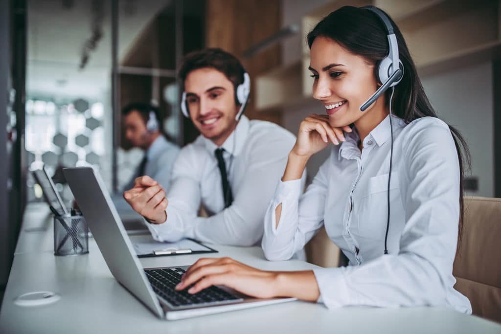 two IT specialists with headsets work at desk at IT company