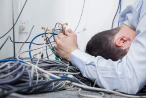 frustrated IT company employee holding tangle of wires due to aging phone system