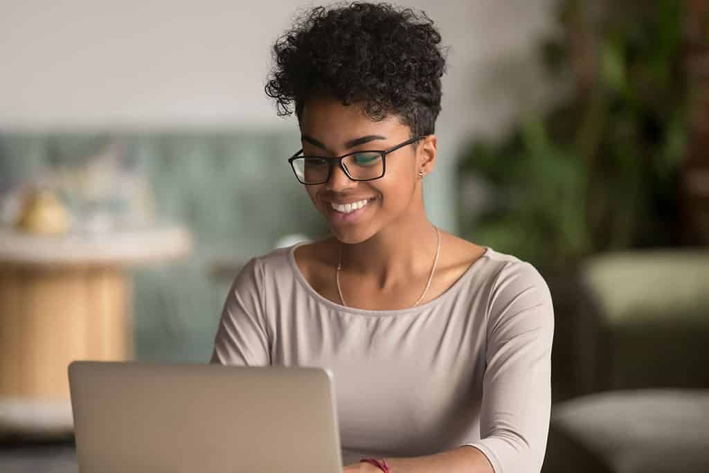 Happy african american woman uses laptop as IT company employee